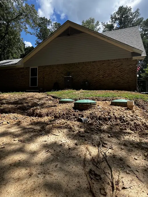 A completed Seal Digging septic install, four green riser lids set across a backfilled Florence yard