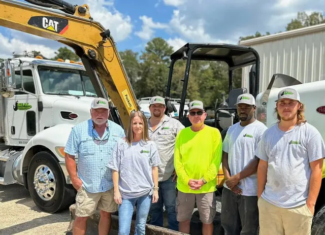 The Seal Digging Service crew standing between a vacuum truck and a tracked excavator at the Florence yard